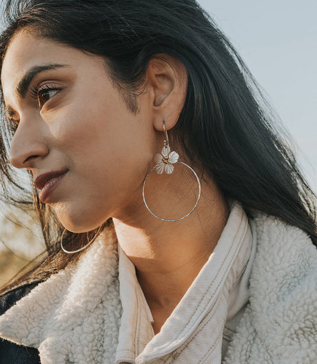 Woman wearing hoop earrings with a blurred natural background