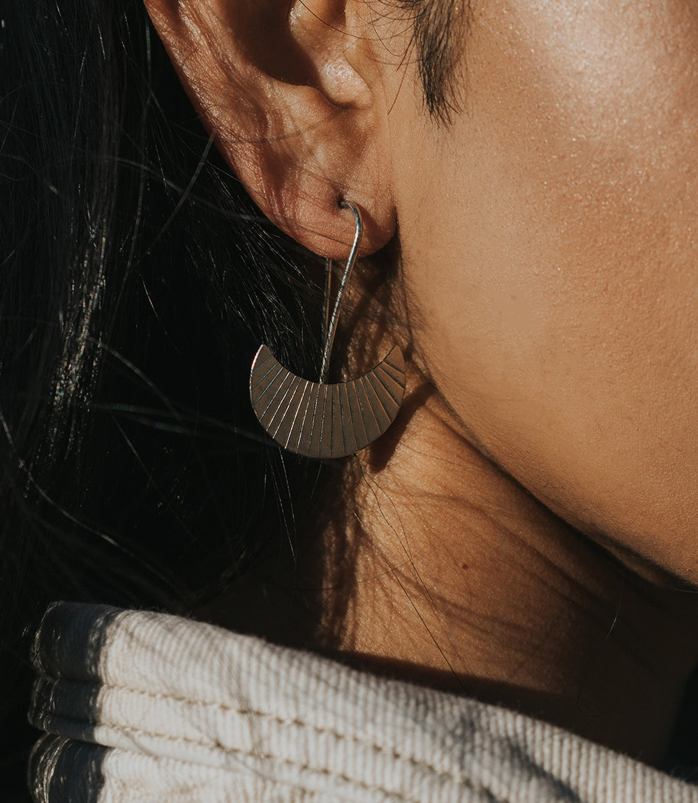 Close-up of a person wearing a gold hoop earring with a blurred background