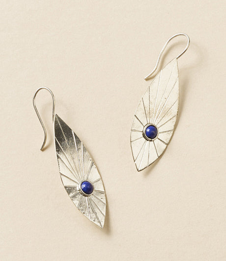 Pair of silver earrings with blue gemstones on a beige background
