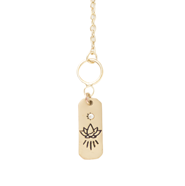 Gold necklace with a tag featuring a lotus flower design on a white background
