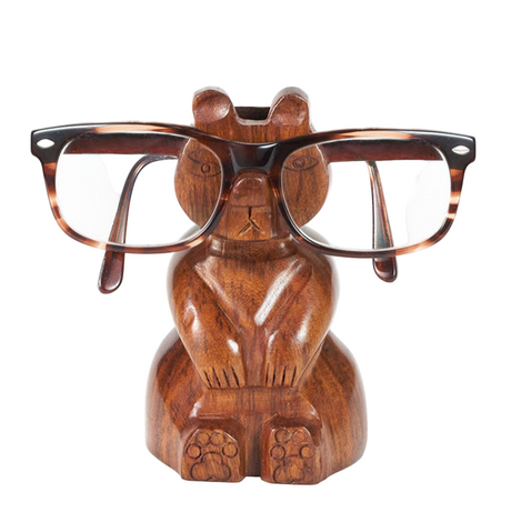 Wooden bear-shaped eyeglass holder with tortoiseshell glasses on a white background