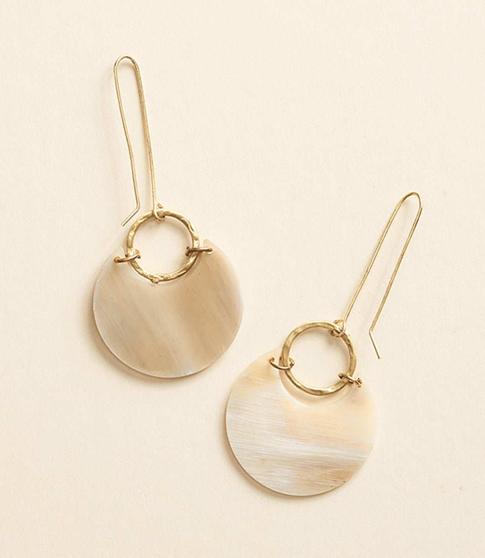 Pair of gold earrings with circular designs on a beige background