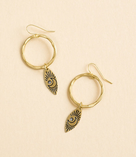 Gold hoop earrings with eye-shaped charms on a beige background