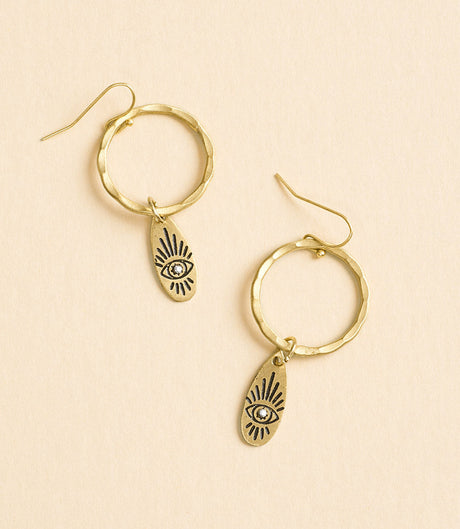Gold hoop earrings with eye-shaped charms on a beige background