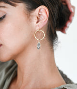 Close-up of a gold hoop earring with a small decorative element worn by a person.