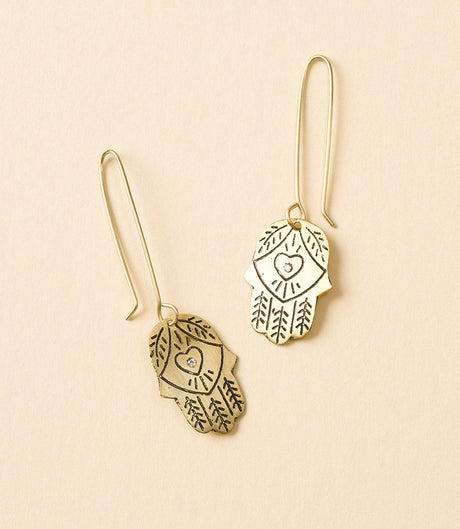 Gold Hamsa hand earrings with heart designs on a beige background