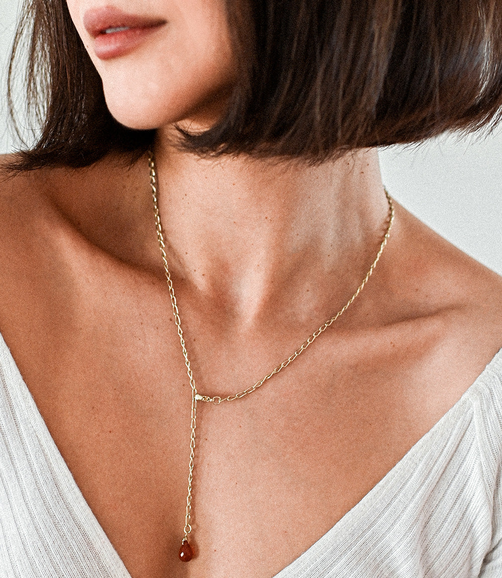 Close-up of a person wearing a delicate gold necklace with a small pendant.