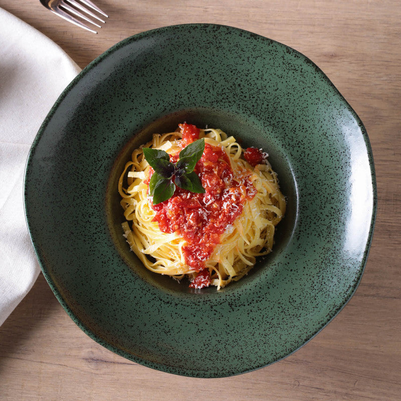 Green bowl with spaghetti and tomato sauce on a wooden table