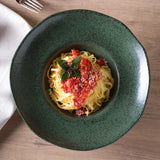 Green bowl with spaghetti and tomato sauce on a wooden table