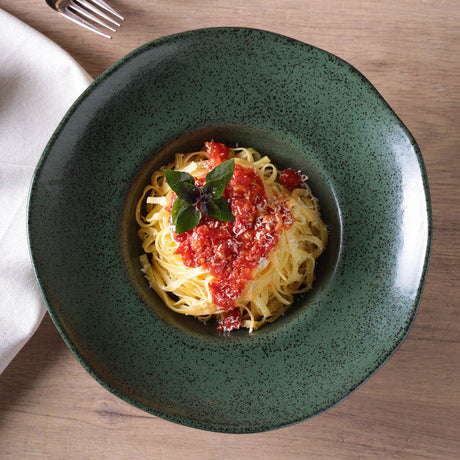 Green bowl with spaghetti and tomato sauce on a wooden table