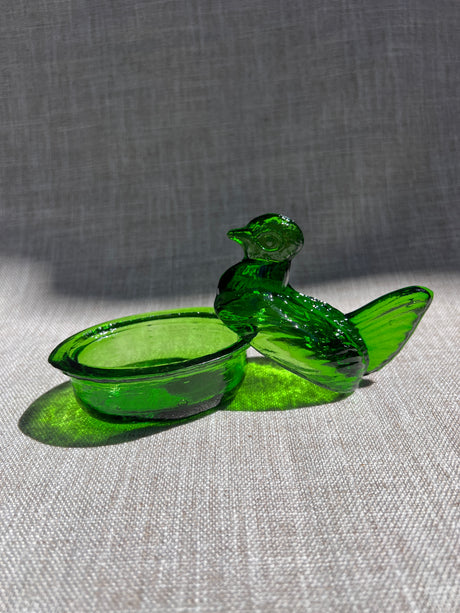 Green glass nesting hen bowl & lid on a gray fabric background
