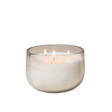 Glass candle holder with a lit candle on a white background