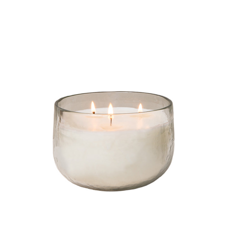 Glass candle holder with a lit candle on a white background