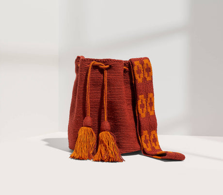 Brown woven bag with tassels on a white background