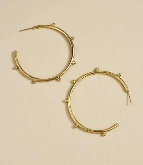 Gold hoop earrings on a beige background