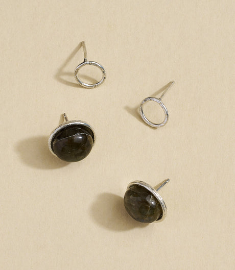 Pair of silver earrings with dark gemstones on a beige background