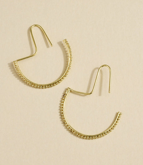 Gold hoop earrings on a beige background