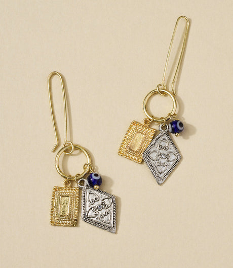 Pair of gold and silver earrings with blue beads on a beige background