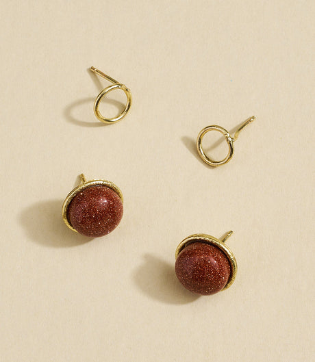 Gold and red stone earrings on a beige background