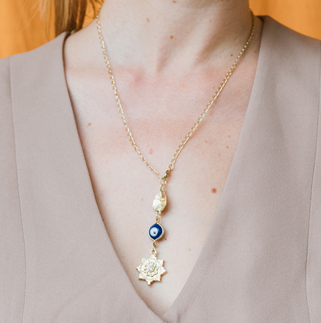 Necklace with floral pendant worn by a person against an orange background