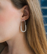 Close-up of a person wearing a silver hoop earring with a blurred background