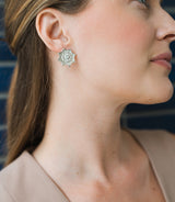 Close-up of a woman wearing a silver floral earring against a blurred background