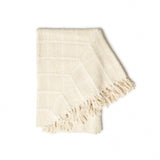 Beige woven blanket with frayed edges on a white background