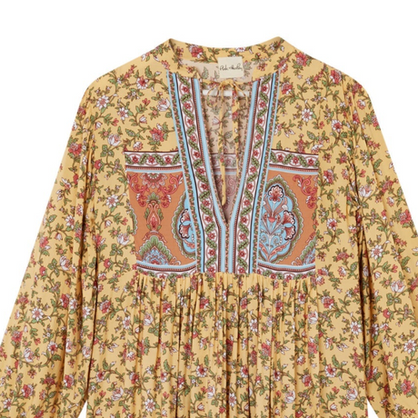 Yellow floral and paisley patterned blouse on a white background
