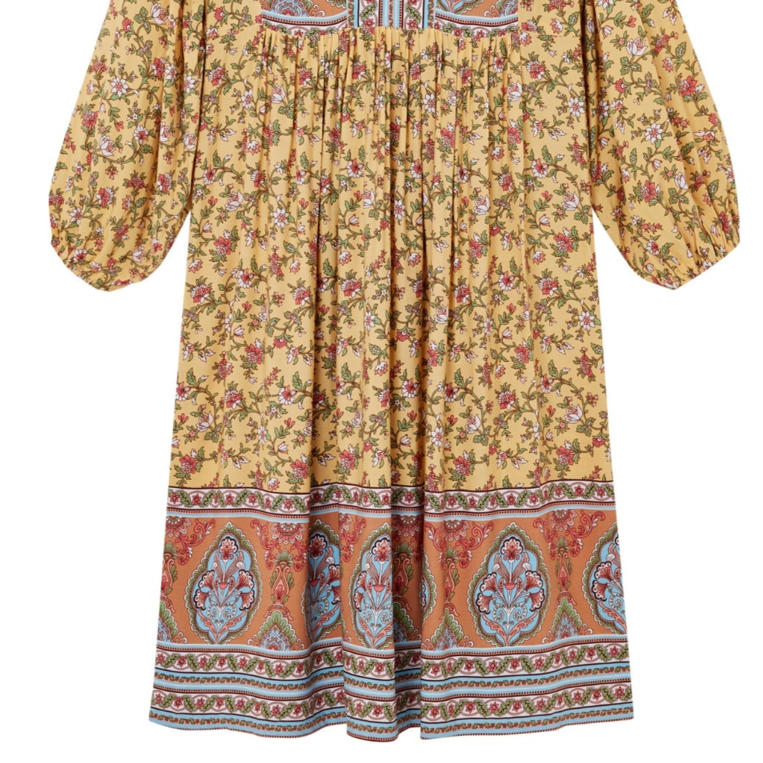 Yellow floral dress with patterned hem on a white background