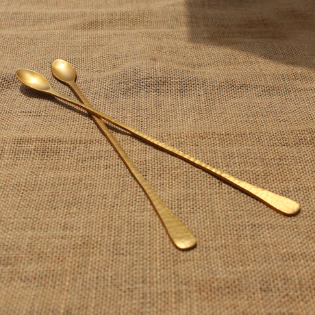 Two gold spoons on a textured brown fabric background