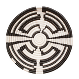 Round woven basket with black and white spiral pattern on a light beige background