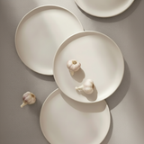 White ceramic plates with garlic on a gray background