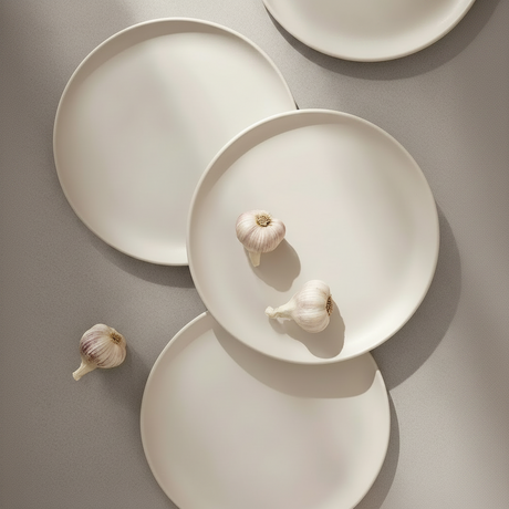 White ceramic plates with garlic on a gray background