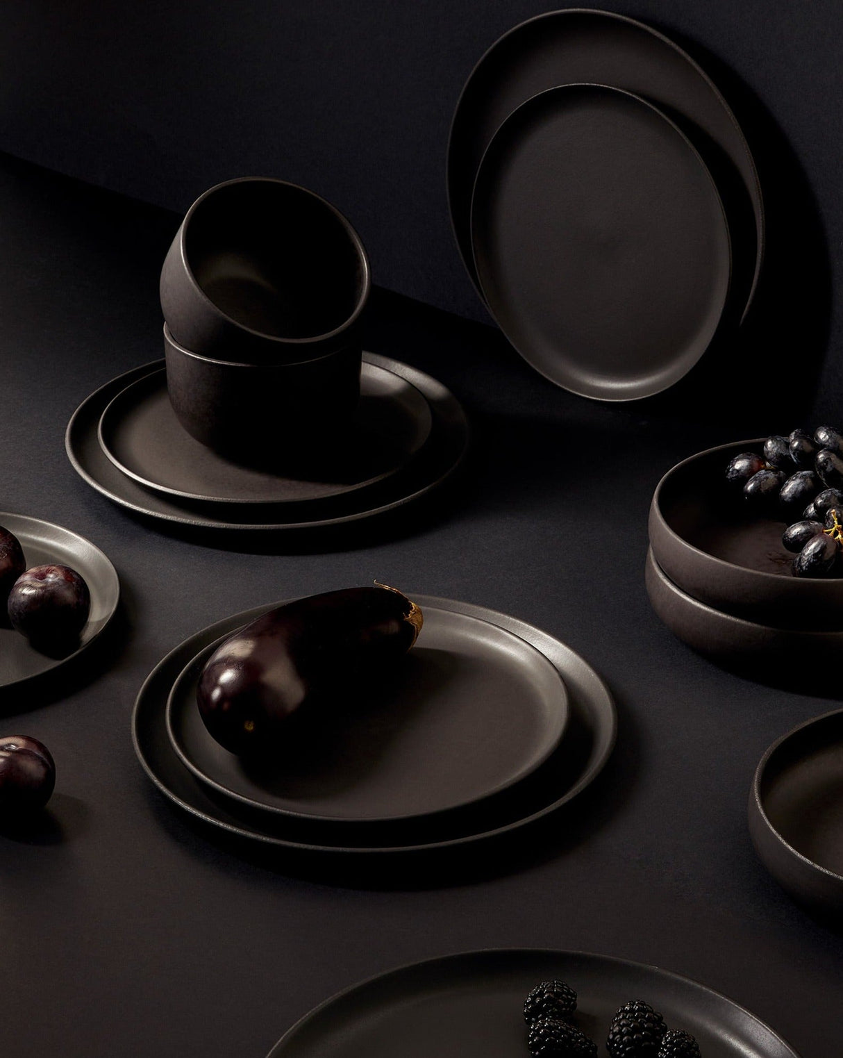 Dark ceramic plates and bowls on a black background