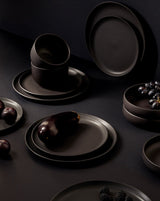 Dark ceramic plates and bowls on a black background