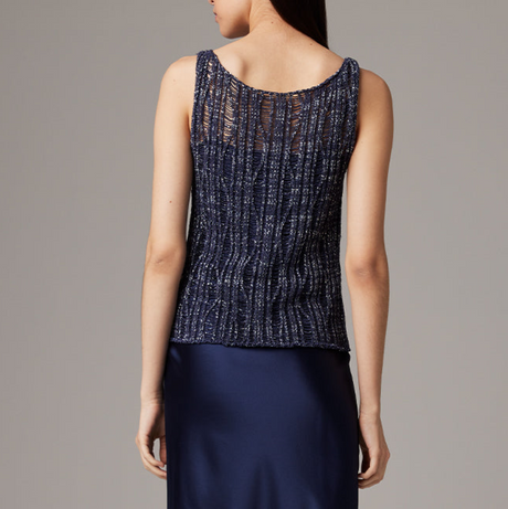 Woman wearing a dark blue sleeveless top with a textured pattern on a gray background