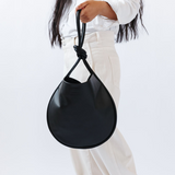 Person holding a black handbag against a white background