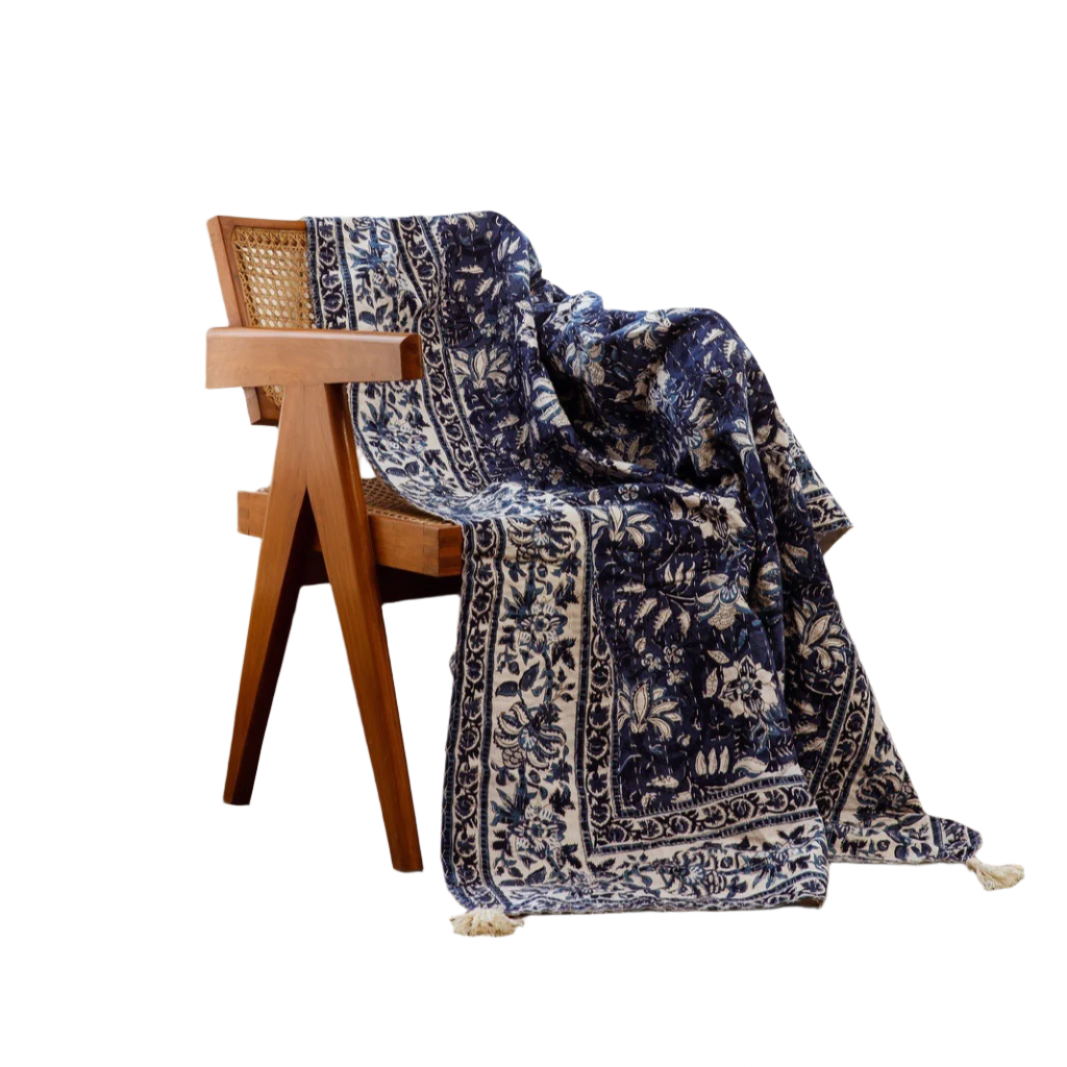Navy floral patterned throw blanket draped over a wooden chair on a white background