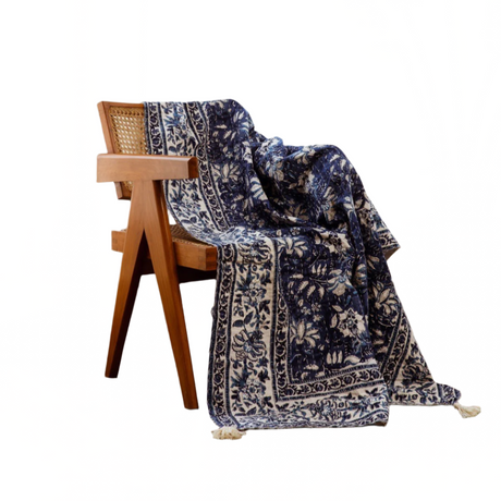 Navy floral patterned throw blanket draped over a wooden chair on a white background