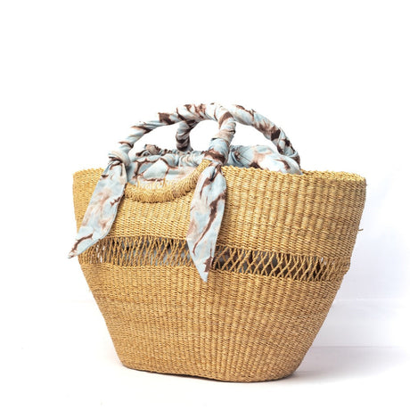 Woven straw bag with floral handle on a white background