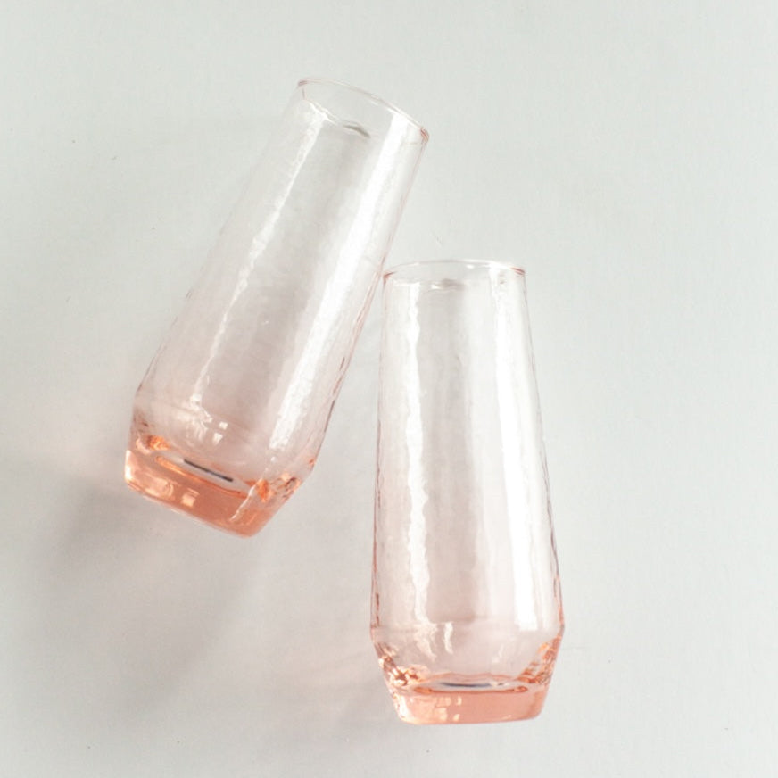 Two clear glass vases with pinkish tint on a light gray background