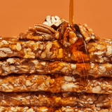 Stack of nutty bars with a drizzle of honey on an orange background