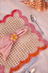 Decorative placemat with pink napkin and floral napkin ring on a pink surface.