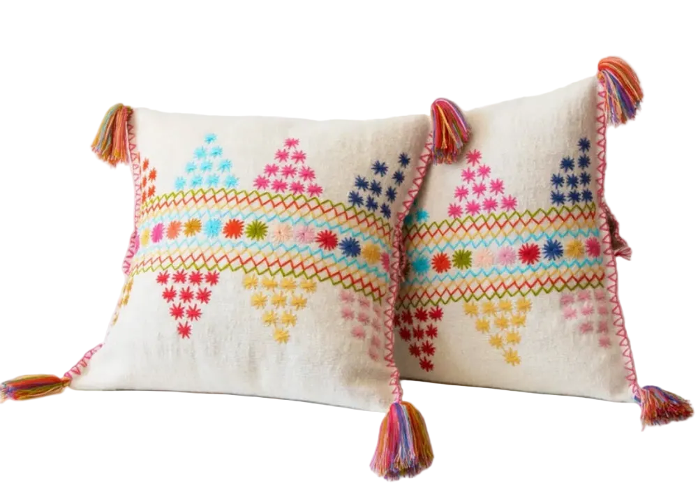 Decorative pillow with colorful embroidery and tassels on a white background