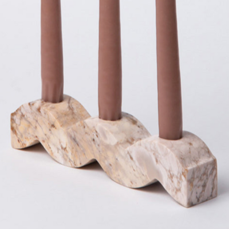 Decorative candle holder with wavy design holding three candles on a light background