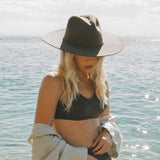 Woman wearing a black hat and black bikini top by the water