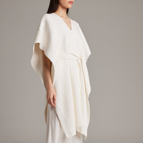 White dress with a draped design on a plain background