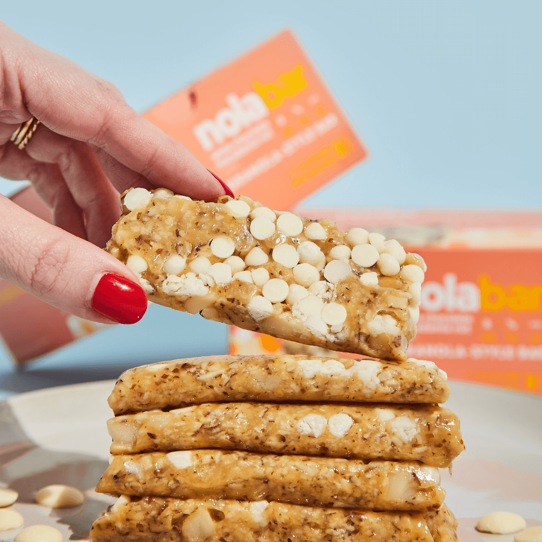 Stack of white chocolate chip cookies with a hand holding one above them, against a light blue background.