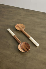 Two wooden ladles with white handles on a brown surface