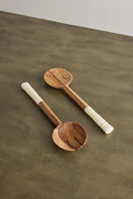 Two wooden ladles with white handles on a brown surface